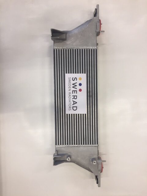 En silver intercooler med svarta fenor, märkt "Intercooler Nissan", är placerad mot en vit bakgrund.
