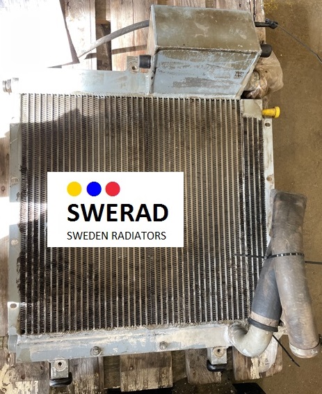 Bild på en begagnad metallradiator märkt "Kylare Atlas lastmaskin" med "SWERAD"-logotypen och slogan "Sweden Radiators." Den visar tecken på slitage och smuts, med bifogade rör och komponenter, placerade på en träyta.